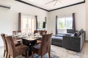 a dining room with a table and chairs and a couch at Brand New Pool Manor Park with WIFI centrally-located in Kingston