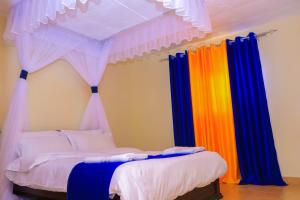 - une chambre avec un lit et des rideaux colorés dans l'établissement Cool and Calm Homes, à Homa Bay