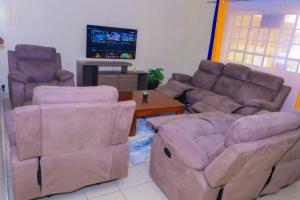 - un salon avec un canapé, des chaises et une télévision dans l'établissement Cool and Calm Homes, à Homa Bay