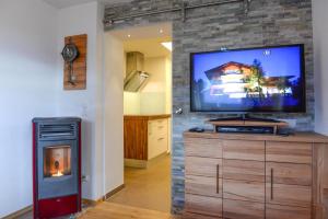 ein Wohnzimmer mit einem Flachbild-TV an einer Steinmauer in der Unterkunft Apartmenthaus Vergissmeinnicht in Abtenau