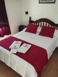 a bed with two white and red pillows on it at Hotel Romi in Colonia del Sacramento