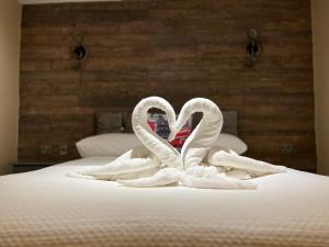 dos cisnes con forma de corazones sentados en una cama en The Commongate Hotels en Londres