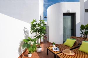 Un balcón con bancos de madera y macetas. en Avanti Clavel, la terraza te conquistará, en Sevilla