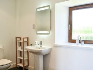 La salle de bains est pourvue d'un lavabo, d'un miroir et de toilettes. dans l'établissement The Byre Camp Douglas, à Crossmichael