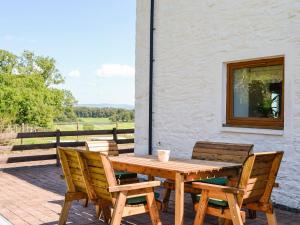Une table et des chaises en bois sont disponibles sur la terrasse. dans l'établissement The Byre Camp Douglas, à Crossmichael