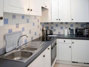 a kitchen with white cabinets and a sink at Stonehanger 1 in Salcombe