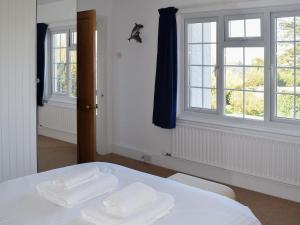 a bedroom with two white towels on a bed with windows at Stonehanger 1 in Salcombe