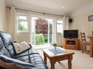a living room with a couch and a tv and a table at St Elmo Lodge in Salcombe