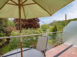 a table and chair with an umbrella on a balcony at St Elmo Lodge in Salcombe