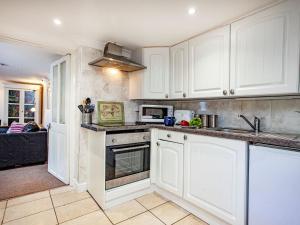 a kitchen with white cabinets and a stove top oven at Westerlands Apartment in Torquay