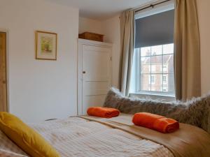 1 dormitorio con 1 cama con almohadas de color naranja en Fox Cottage en Beverley