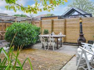un patio con mesa, sillas y una valla en Fox Cottage, en Beverley