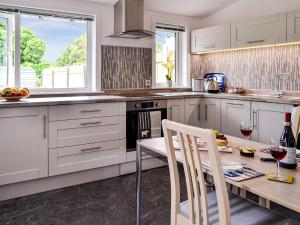 a kitchen with white cabinets and a table with two chairs at Park Crescent in Creetown