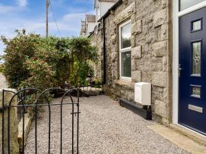 a stone house with a blue door and a bush at Park Crescent in Creetown