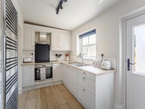 Chatton的住宿－Farmside Cottage-uk35018，厨房配有白色橱柜、水槽和窗户。