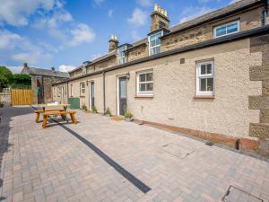 a patio with a picnic table in front of a building at Farmside Cottage-uk35018 in Chatton