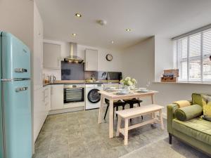 uma cozinha com uma mesa e um frigorífico azul em Heron Apartment em Berwick-Upon-Tweed