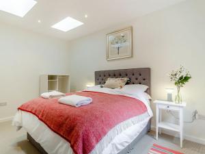 sypialnia z dużym łóżkiem i czerwonym kocem w obiekcie Church Garden Cottage w mieście Higham