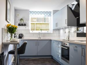 una cocina blanca con armarios azules y fregadero en No1 Park Lodge en Buxton