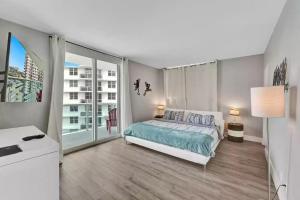 a white bedroom with a bed and a large window at Amazing Apartment on hollywood beach TIDES in Hollywood