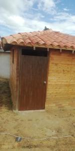 a wooden garage with a brown door with a red roof at Casa de Barro Ecodomo in Los Santos