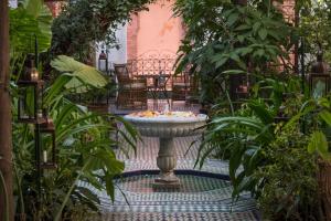 einen Brunnen inmitten eines Gartens mit Pflanzen in der Unterkunft Palais Riad Lamrani in Marrakesch