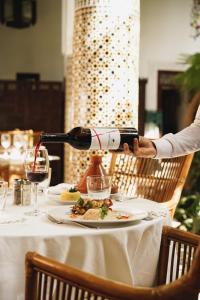 une personne versant du vin dans une assiette de nourriture dans l'établissement Palais Riad Lamrani, à Marrakech