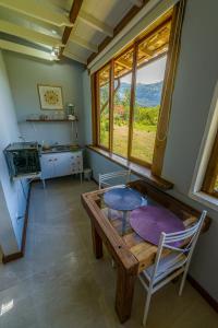 a kitchen with a table and a table and a window at Pousada Mandala das Águas in Aiuruoca