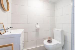 a white bathroom with a toilet and a sink at Old Chelsea in Deal