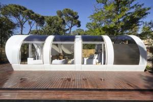 un edificio con puertas blancas y ventanas en una terraza de madera en Tubbo Experience by Camping Osuna, en Madrid