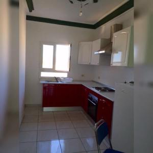 a small kitchen with red cabinets and a window at Residence Nadia in Tabarka