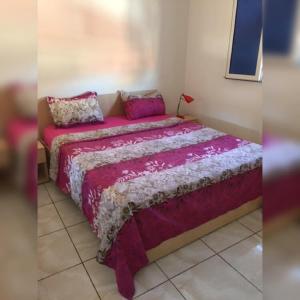 Una cama con una manta rosa y almohadas. en Residence Nadia en Tabarka