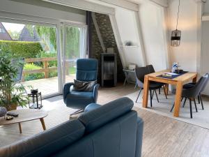 uma sala de estar com um sofá, cadeiras e uma mesa em Murmel 2 - Wallbox, WLan, Kamin em Greetsiel