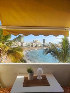 een raam met uitzicht op een strand en gebouwen bij Francisco's Holiday Home in Las Palmas de Gran Canaria