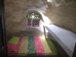 a room with a bed in a cave with a window at Casa de Barro Ecodomo in Los Santos