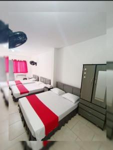 drie bedden in een kamer met rode en witte lakens bij Hotel Gueicer Cucuta in Cúcuta