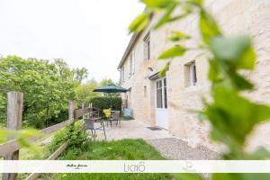 eine Terrasse mit Stühlen und einem Sonnenschirm neben einem Gebäude in der Unterkunft Le Cosy-vergerentre2mers in Langoiran