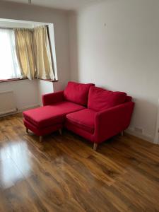 a red couch in a living room with wooden floors at NKY Sweet 3 Bed House Apartment in London