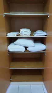 a closet with shelves with white pillows and towels at Conforto e tranquilidade, 2 quartos, próximo à praia in Maceió