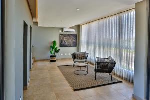 a living room with two chairs and a table and a large window at Zimbali Lakes Boulevard Suites 103 in Ballito