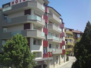 un edificio de apartamentos alto con balcones rojos y blancos en ALPHA family HOTEL, en Blagoevgrad