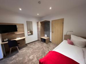 a bedroom with a bed and a desk and a television at Hotel & Restaurant Zum Karpfen in Obernburg am Main +18 photos