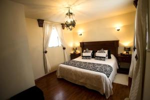 a bedroom with a bed with a chandelier and a window at Roka Plaza Hotel Boutique in Ambato +80 photos