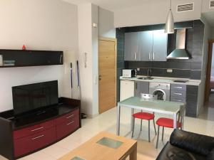 ein Wohnzimmer mit einem Tisch und einer Küche in der Unterkunft Apartamentos El Palo in Málaga