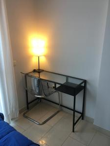 einen Glasschreibtisch mit einer Lampe an der Ecke eines Zimmers in der Unterkunft Apartamentos El Palo in Málaga