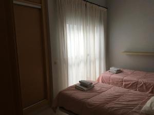 2 Betten in einem Zimmer mit Fenster in der Unterkunft Apartamentos El Palo in Málaga