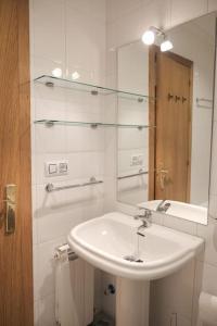 a white bathroom with a sink and a mirror at La casina de cori in Luarca