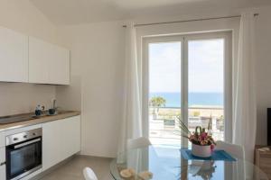 cocina con mesa de cristal y vistas al océano en Villa Taliala, en Alcamo Marina