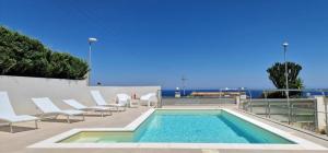 una piscina con tumbonas blancas y una piscina en Villa Taliala, en Alcamo Marina