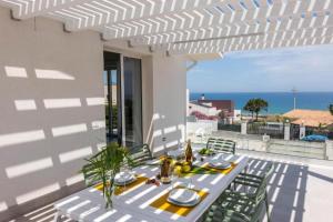 a white table with chairs on a patio with the ocean at Villa Taliala in Alcamo Marina